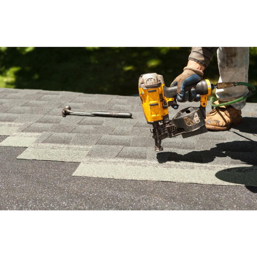Close up of person on roof attaching shingles with power tool.